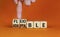 Adaptable or flexible symbol. Businessman turns wooden cubes and changes the word Adaptable to Flexible. Beautiful orange table