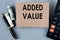 ADDED VALUE - words on brown paper on the background of a calculator, banknotes and pen