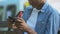 Addicted Afro-American male teenager nervously playing video game on smartphone