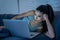 Addicted beautiful woman working and chatting on her laptop late at night looking exhausted