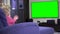 Addicted little girl point finger and wave looking tv. Green chroma key screen