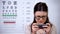 Addicted woman in eyeglasses playing video game on smartphone, vision problem