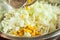 Adding canned corn from a jar to a plate with fresh onion sliced for salad in a plate, closeup