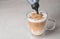 Adding caramel topping to latte macchiato on table