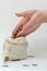 Adding coins to a small bag of money. Hands close-up. Falling coins. Vertical photo, white background. Concept - enrichment