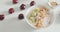 Adding granola, kiwi and cherry into strawberry yogurt bowl. Preparing Healthy low calorie high protein and fiber breakfast.