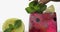 Adding leaves of mint in a glass with cold drink, lime, lemon, currants, ice