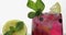 Adding leaves of mint in a glass with cold drink, lime, lemon, currants, ice