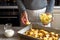 Adding potato in the baking tray with ingredients for tartiflette