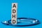 Adhd letters word written on wooden blocks and stethoscope on light blue background
