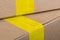 Adhesive yellow packing tape on a cardboard box. Selected focus, close-up. Delivery or moving concept. Beige cardboard