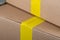 Adhesive yellow packing tape on a cardboard box. Selected focus, close-up. Delivery or moving concept. Beige cardboard