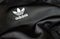 The Adidas logo sewn on a black recycled polyester fabric. Sportswear and iconic logo. Famous German sportswear brand.