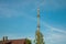 Adio mast for the mobile phone network towers above a residential building into the blue sky in a residential area