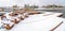 Adirondack wooden chairs on a deck overlooking lake and houses in winter