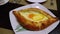 Adjarian Khachapuri on a Table in a Georgian Restaurant. Open Bread Pie with Egg Yolk