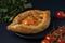 Adjarian Khachapuri â€“ Georgian cheese bread with tomatoes and parsley on dark textured background. Baked open pie with cheese