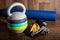 Adjustable kettlebell, cycle gloves dumbbells and yoga mat on wooden background. Weights for a fitness training.