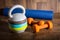 Adjustable kettlebell, pair of orange dumbbells and yoga mat on wooden background. Weights for a fitness training.