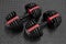 Adjustable weight dumbbell in plastic polymer material on black rubber floor.