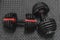 Adjustable weight dumbbell in plastic polymer material on black rubber floor