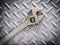 Adjustable wrench close up on checker plate background.