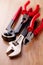 Adjustable wrench, pliers, claw hammer and pliers on the wooden background