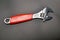 Adjustable wrench with red rubberized handle on black background