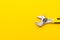 Adjustable wrench with yellow handle on the yellow background with copy space