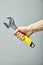 Adjustable wrench with yellow rubberized handle, isolated on gray background