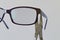 Adjusting inclination of temples on simple plastic eyeglass frame with steel chain nose pliers.