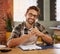 Admin keeps my business running. Portrait of a happy young business owner doing admin at a table in his coffee shop.