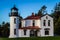 The admiralty Head Lighthouse with classic Pacific Northwest woods behind it