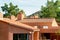 Adobe orange rooftops on multiple buildings in the late afternoon city with back yard trees in natural sunlight