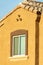 Adobe style house facade with lone window and light roof pannels with orange or brown stucco exterior