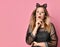 Adolescent in black dress, headband like cat ears, face painting. She posing on pink background. Close up