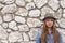 Adolescent girl in a hat and denim jacket against a white stone walls. Walk.