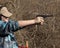 Adolescent girl shooting pistol with brass flying