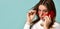 Adolescent in orange sunglasses, watch, bracelet and sweater. She talking by phone, surprised, posing on blue background. Close up