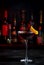 Adonis alcoholic cocktail drink with sherry and red vermouth, black bar counter background, steel tools and bottles