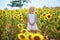 Adorable 4 year old girl in white dress and straw hat in a field of sunflowers, Provence, France