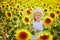 Adorable 4 year old girl in white dress and straw hat in a field of sunflowers, Provence, France