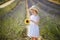 Adorable 4 year old girl in white dress and straw hat walking through rows of lavender near Valensole, France