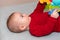 Adorable 6 months old little baby boy on his back surrounded by colourful toys