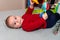 Adorable 6 months old little baby boy on his back surrounded by colourful toys