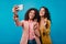 Adorable african girl making selfie. Female friends posing on blue background