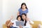 Adorable Asia happy family, cute two daughter girls with mother hold digital tablet, look at web camera and wave hands for