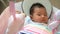 Adorable Asian baby feel sleepy , lying in a swing cradle