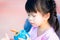 Adorable Asian girl is thirsty  is about to drink from a blue water bottle. Child was thirsty after exercising.