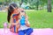 Adorable Asian sister sitting on pink mattress mat take care her little brother to drinking water from Baby sippy cup with straw